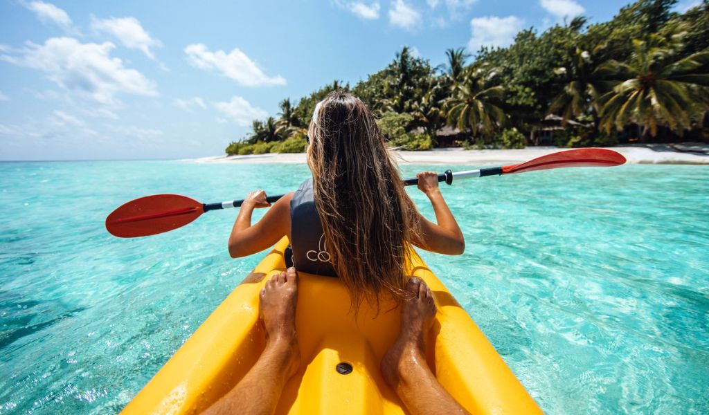 A couple enjoys kayaking on the Maldives beach. 