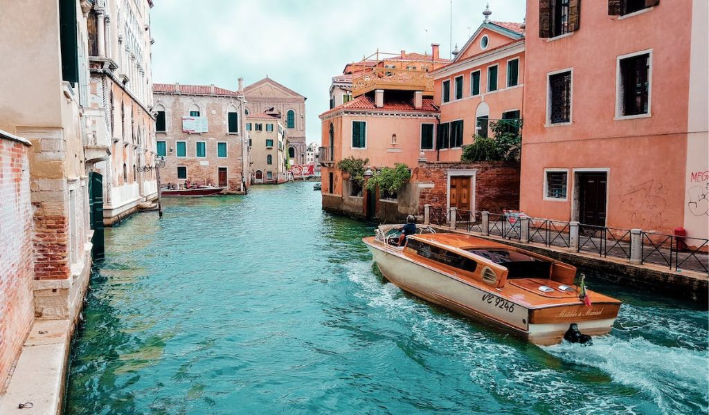 Orange Powerboat Between Medium-Rise Buildings on Venice Lagoon.