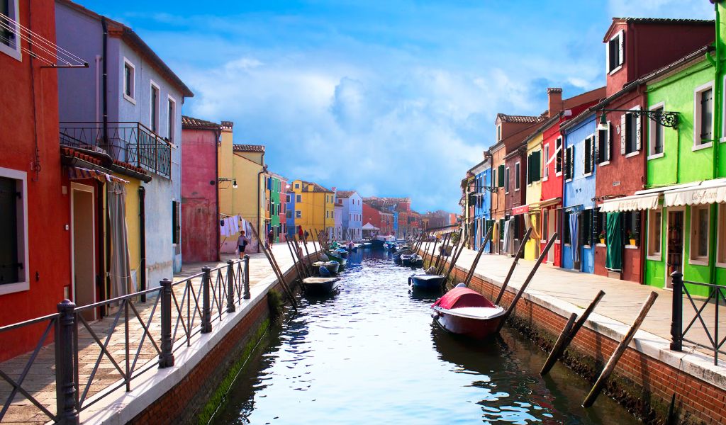 A row of houses with boats along a canal in Murano, Italy.