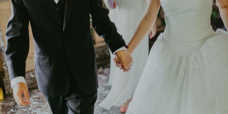 woman wearing white wedding gown holding hands with man