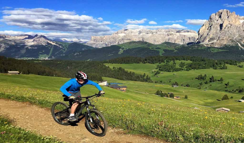 A kid biking on a rough road on the mountain with stunning views of landscapes and mountains in Italy