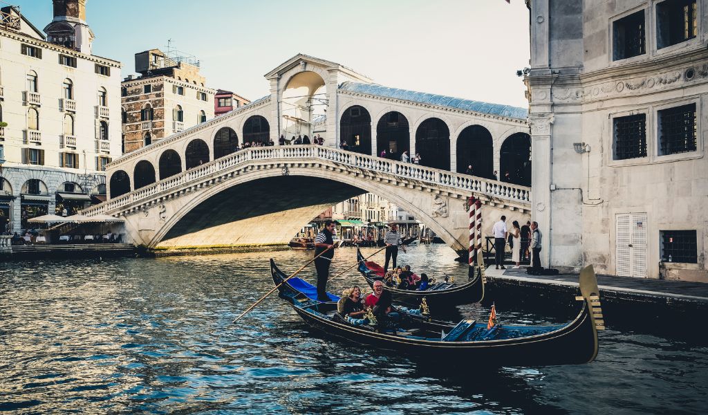Tourists enjoy the tour using a gondola near the Rialto Bridge in Venice, Italy.