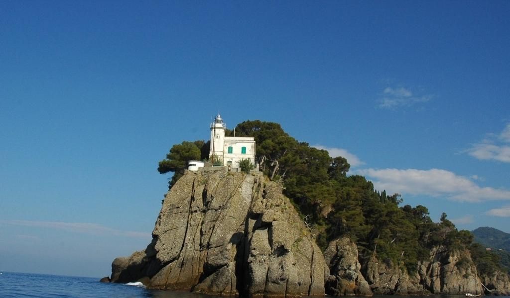 The Faro di Punta del Capo is located on top of the rocky mountain near the sea.