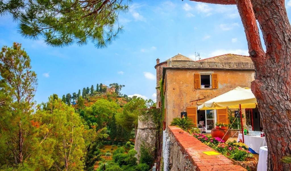 A colorful house surrounded by trees with a view of the old castle in Manarola.